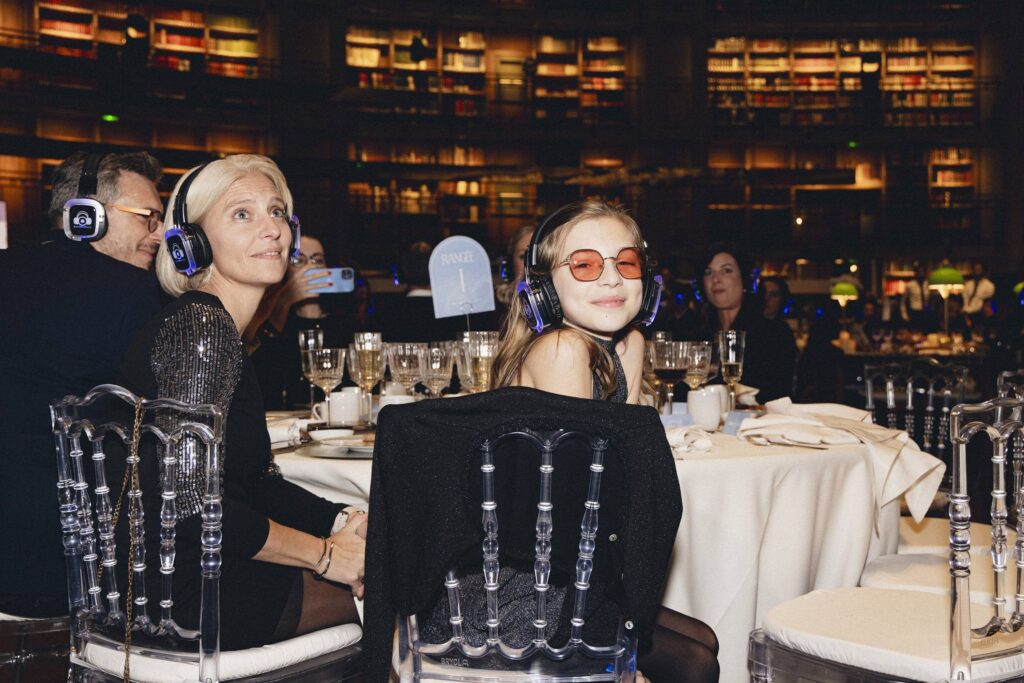 Jeune fille au Gala Make-A-Wish Paris 2025 portant nos casques à table, moment émouvant avec sa maman