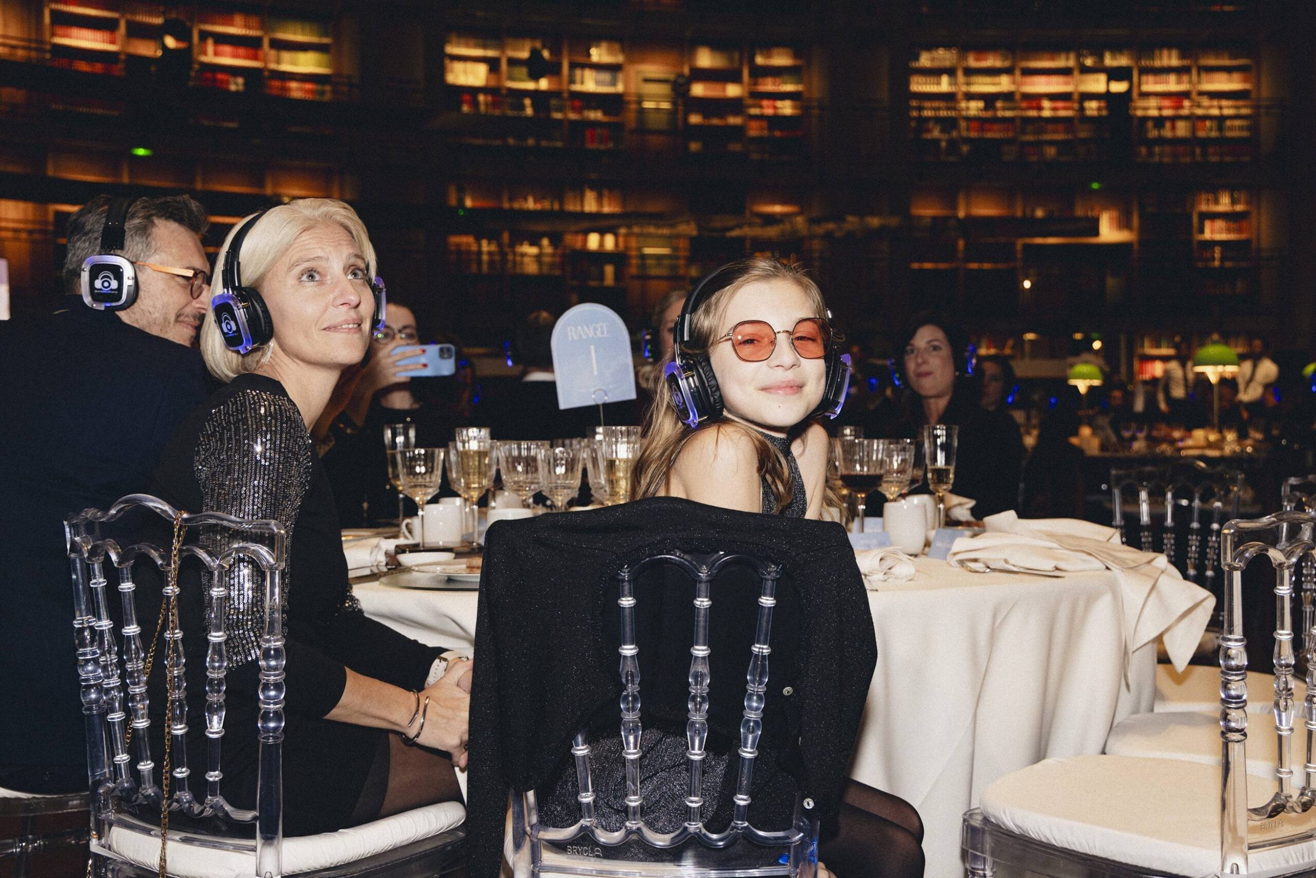 Jeune fille au Gala Make-A-Wish Paris 2025 portant nos casques à table, moment émouvant avec sa maman